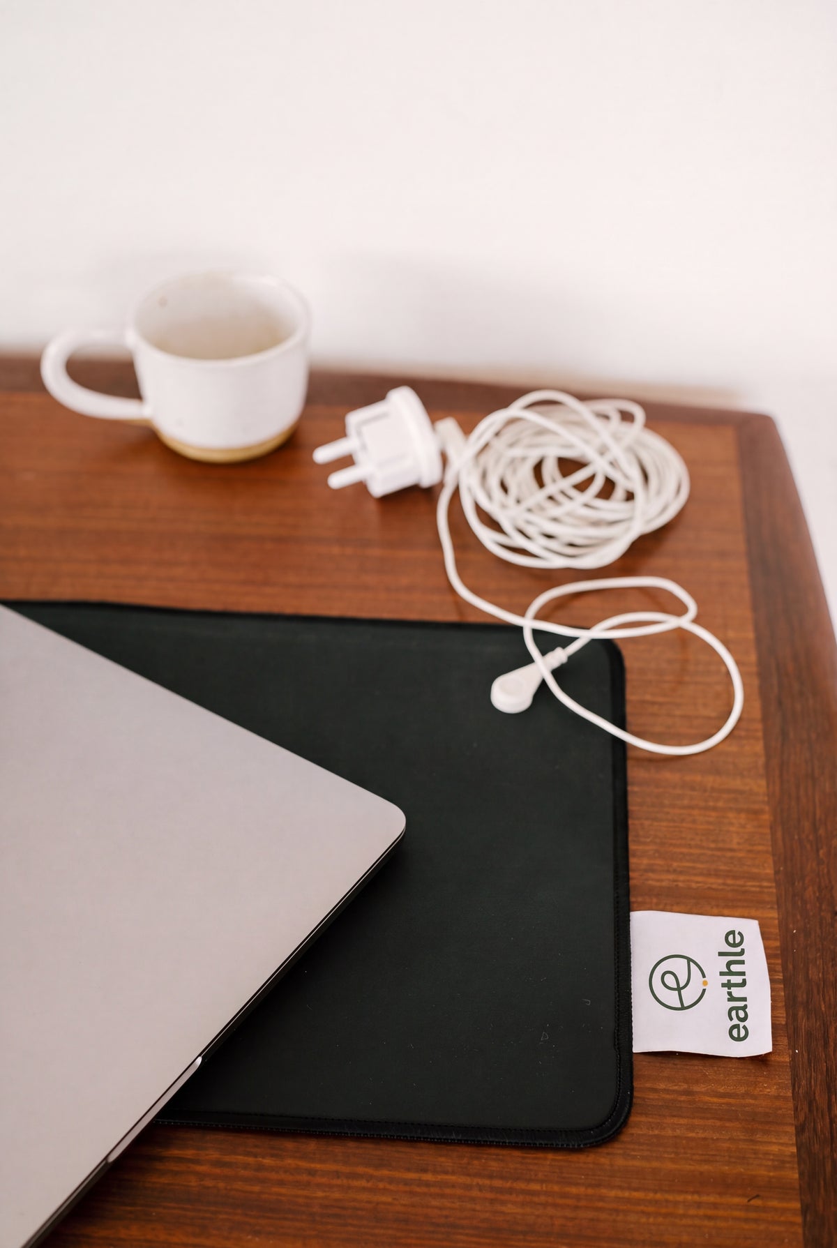Jordningskontakt och upprullad kabel på ett skrivbord bredvid skrivbordsmattan och en bärbar dator