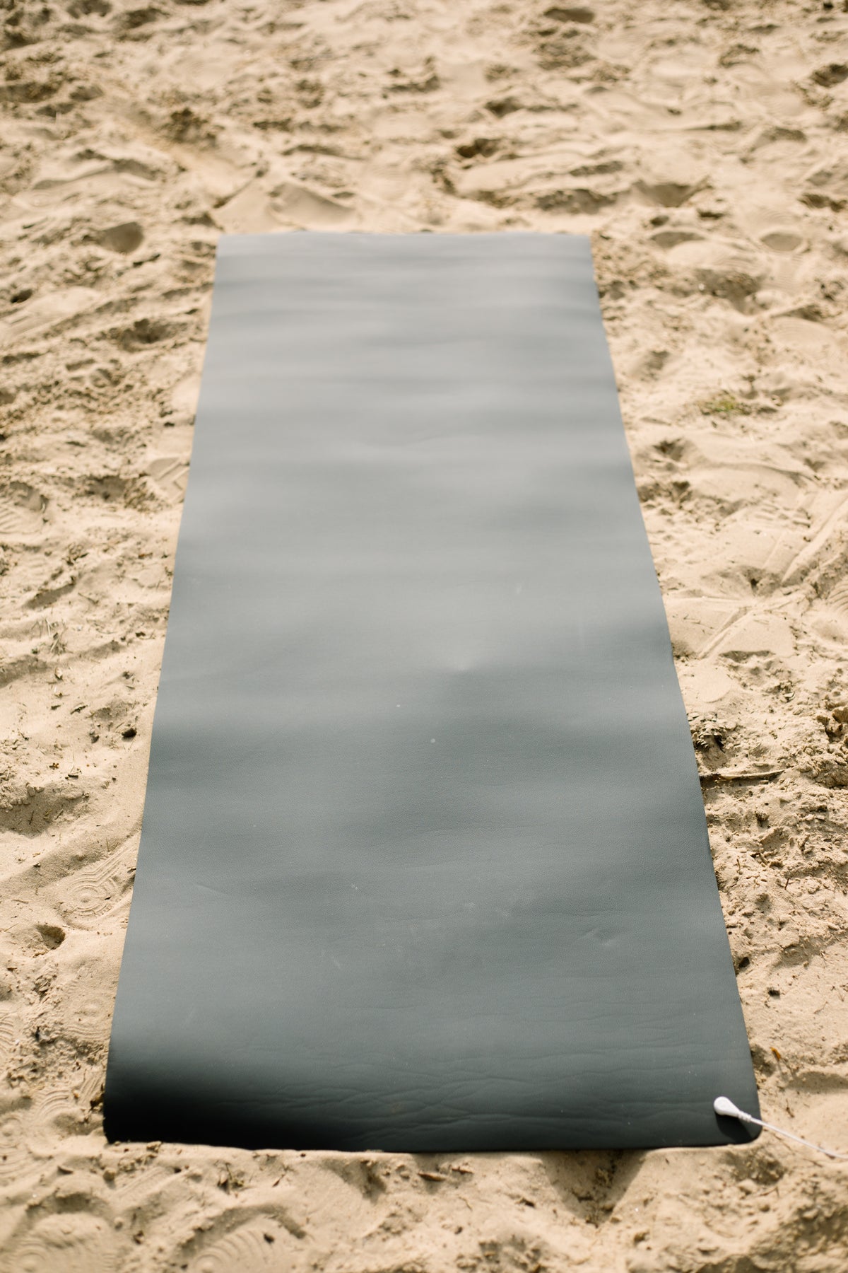 Earthle jordningsyogamatta utrullad i sanden